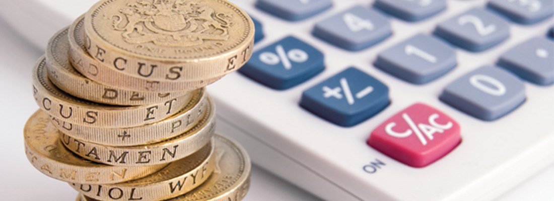 Stack of pound coins next to a calculator.