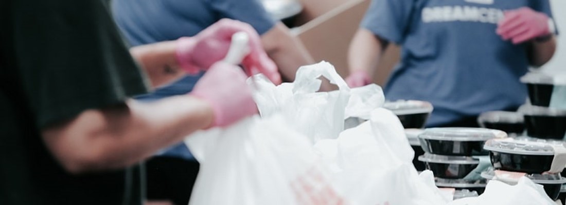 Person collecting a handful of carrier bags with food in it.