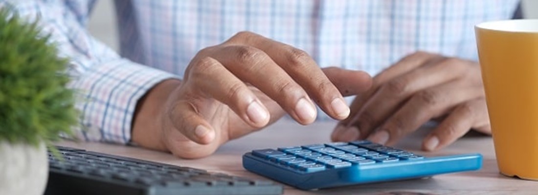 Man's hand typing on a calculator