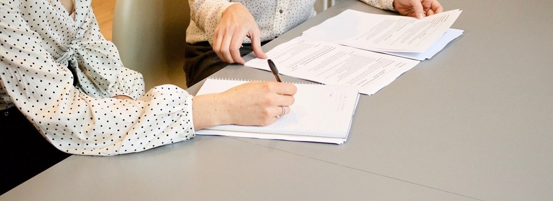 Two women sat at a desk looking at a report.