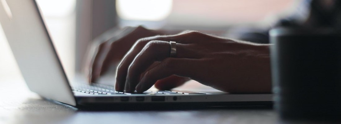 A man's hands typing on a laptop