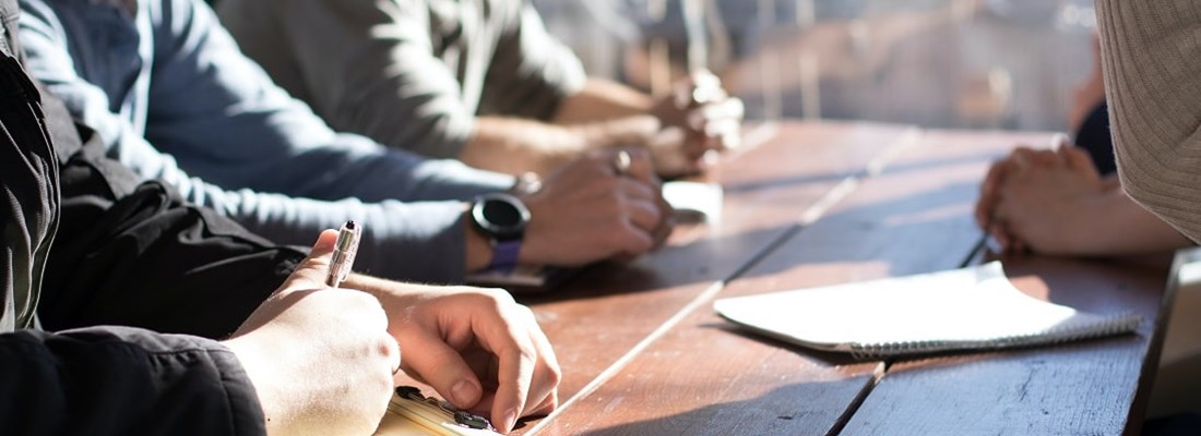 People sitting at a table with notepads.