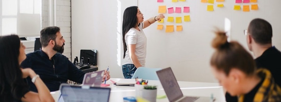 People in an office with Post It notes on the wall.