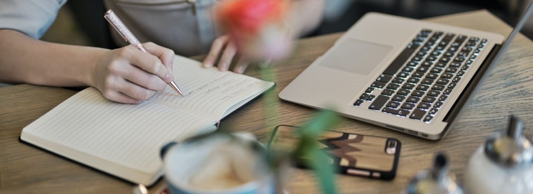 Woman studying and writing in a notepad.