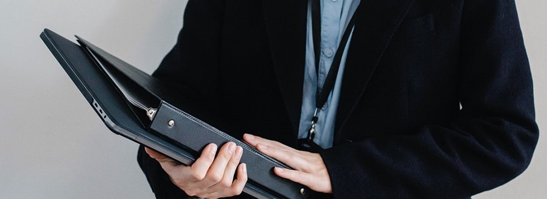 Woman holding a folder and laptop.