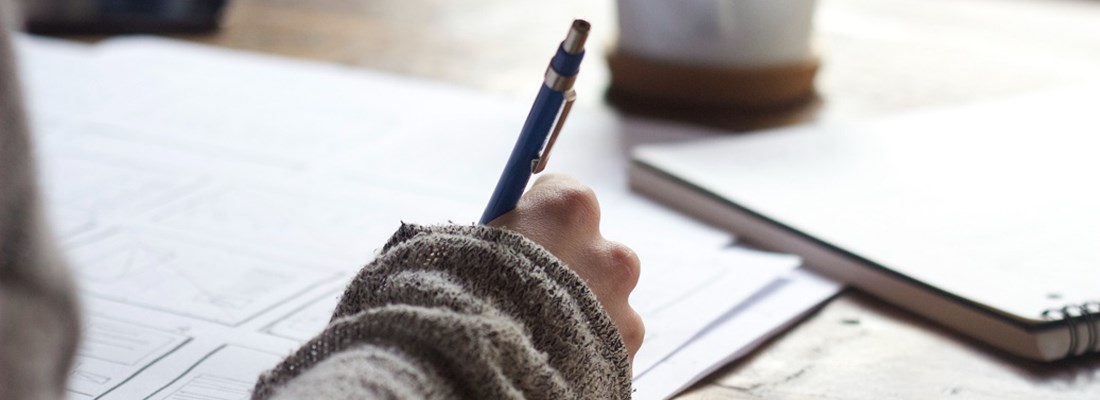 Person writing on paper with pen.