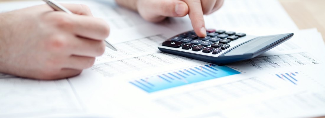 Calculator and papers on desk, person working
