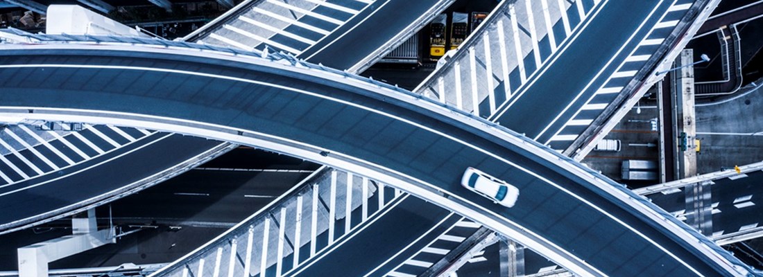 Aerial view of a multi-level highway interchange with vehicles, lane markings, and surrounding urban infrastructure