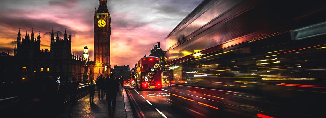 Big Ben and Westminster Bridge at dusk with blurred motion of double-decker buses in London